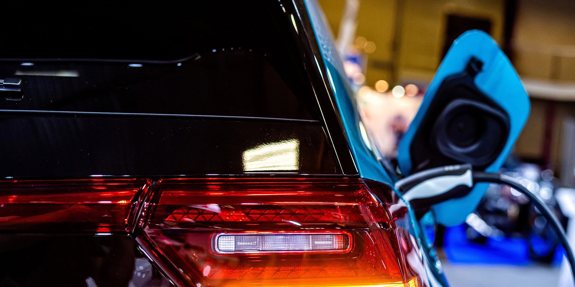 charging an electric car with the power cable supply plugged in, focus on rear lights, selective focus